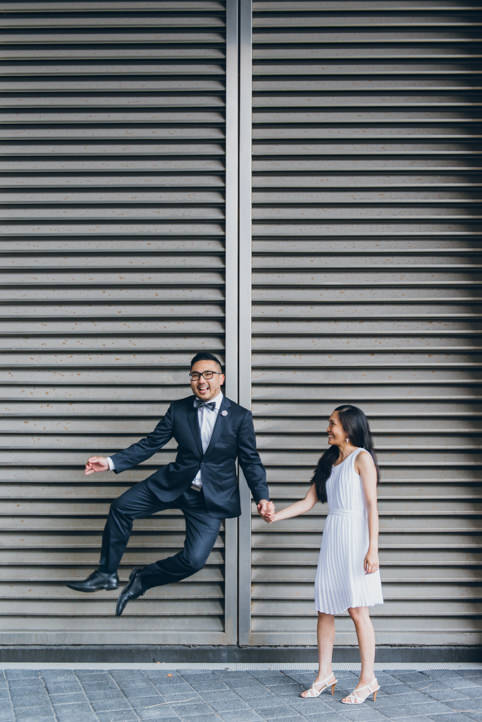 A groom jumps for joy while holding hands with his bride at their Toronto City Hall wedding.