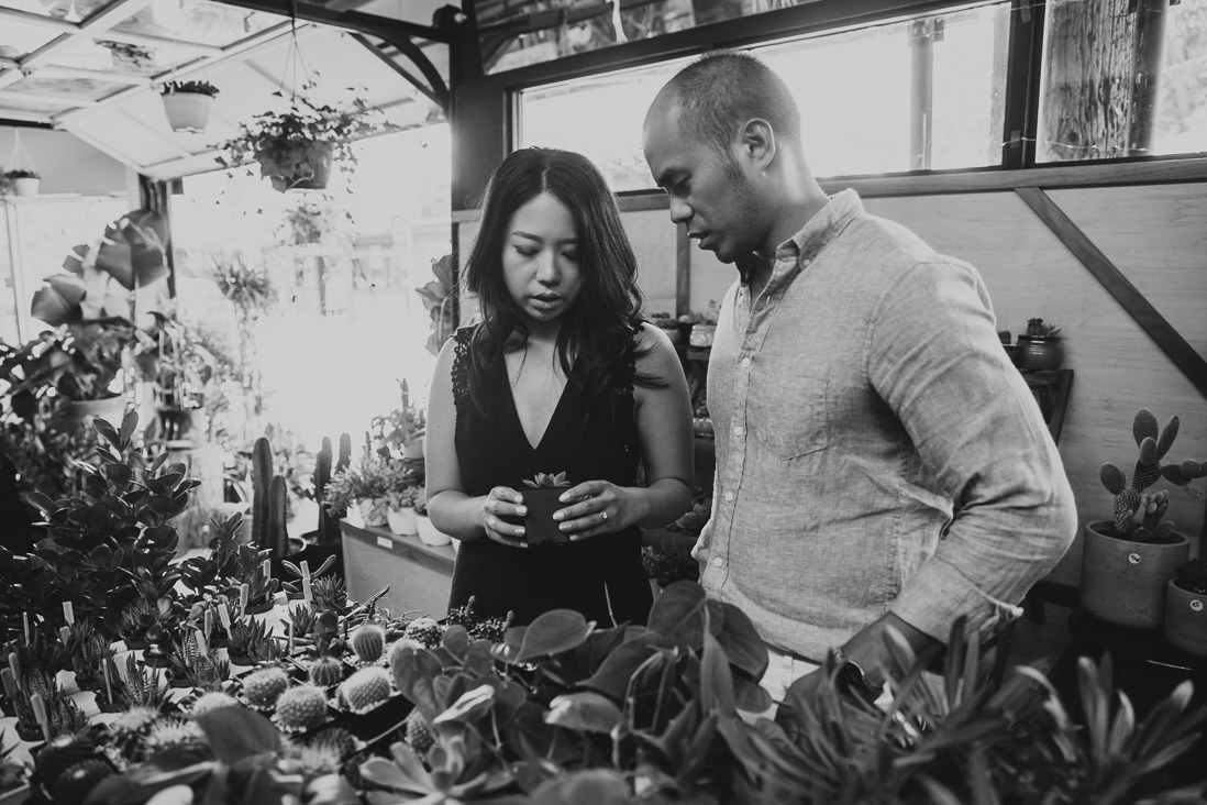 Black & White photo of couple shopping for cacti | Couple laughing in front of plant shop | Kensington Market Engagement, Toronto | EightyFifth Street Photography