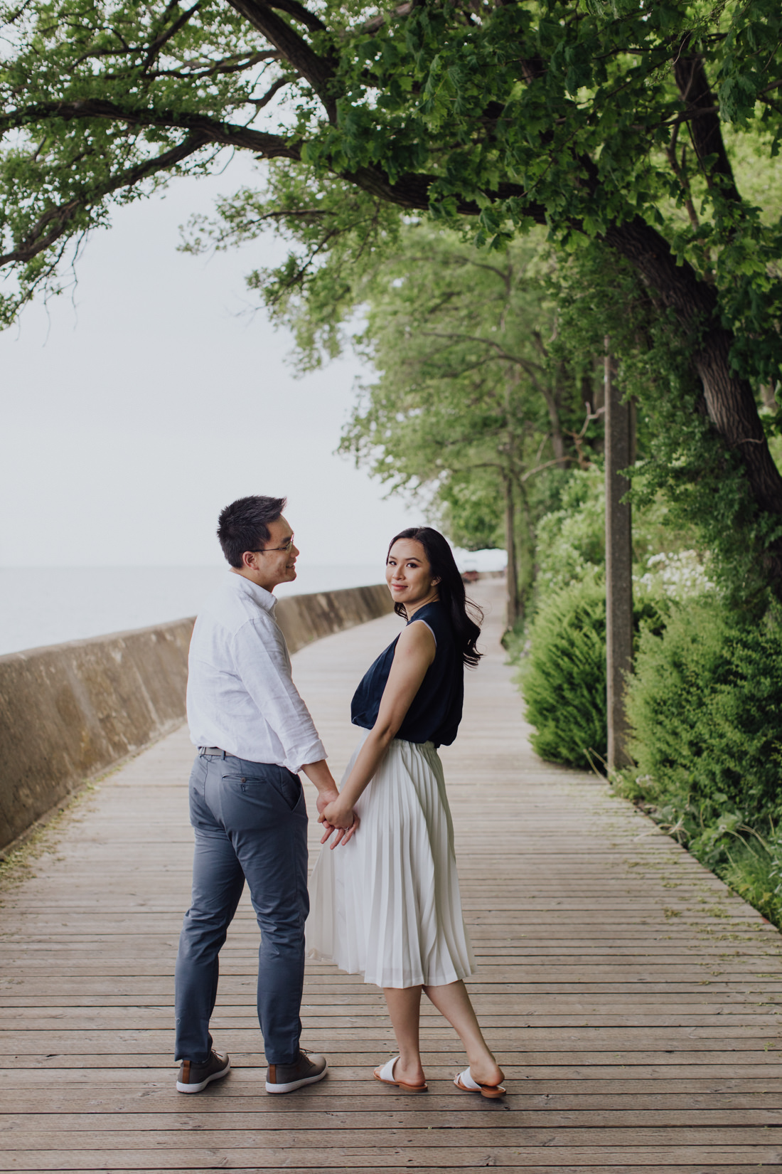 Couple holding hands on boardwalk | Wards Island Engagement | EightyFifth Street Photography
