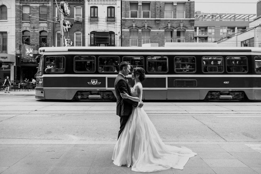 black & white portrait of bride & groom in front of passing street car on king st toronto wedding