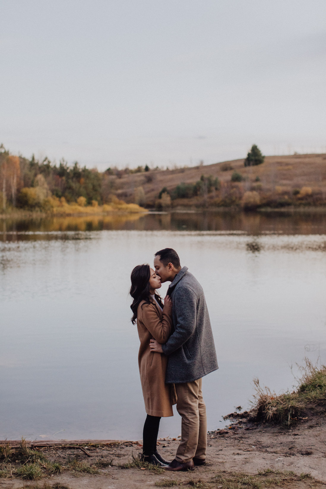 couple kissing in front of still lake fall engagement | eightyfifth street photography