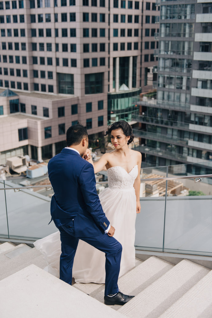 A groom kisses his bride's hand while standing on the steps of the terrace at their Malaparte wedding in Toronto