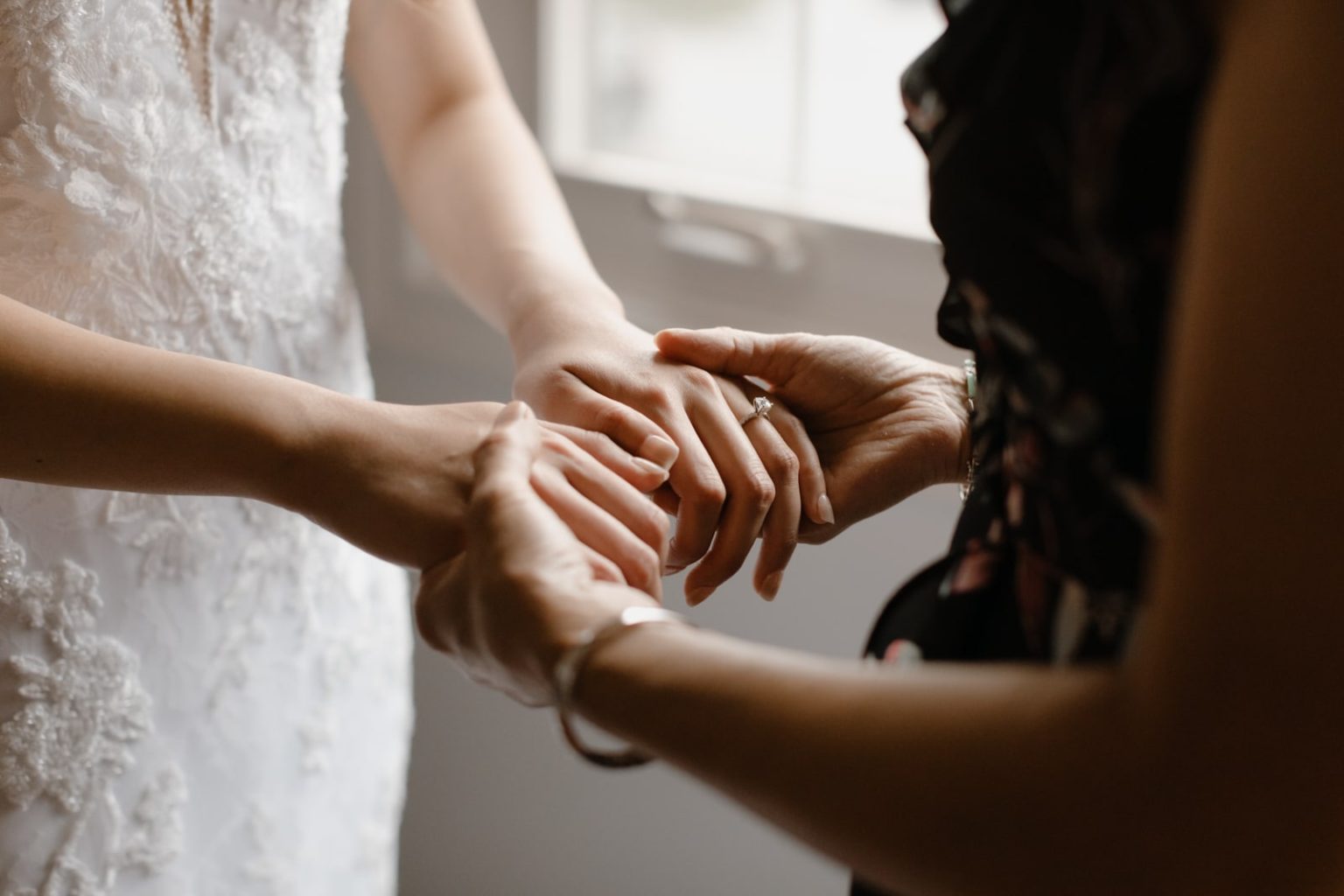 mother holds brides hands during blessing