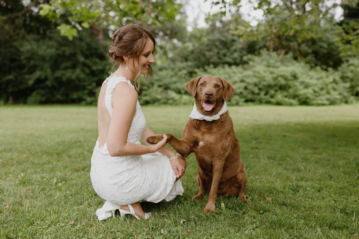 A bride, accompanied by her dog, enjoys a tender moment at the side lawn at her Harding Waterfront Estate wedding in Mississauga.
