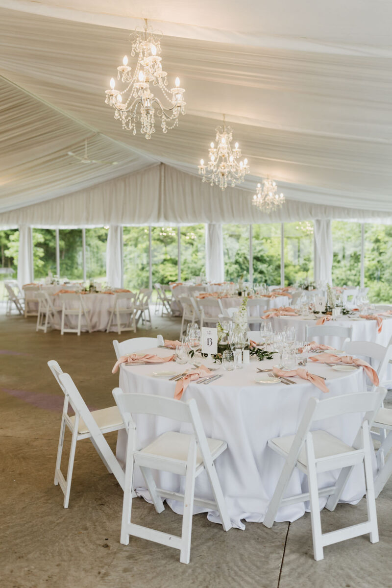 The glass pavilion at Harding Waterfront Estate, set up for a wedding reception with pink napkins, round tables and white chairs.